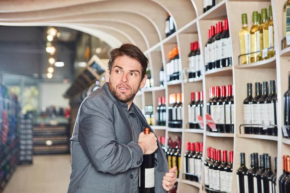 young-man-puts-a-bottle-of-wine-in-his-jacket-during-shoplifting_03